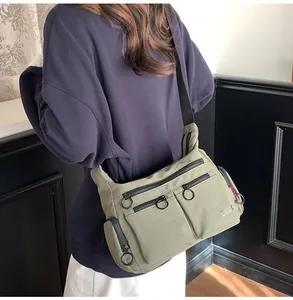 Detail of army green nylon crossbody bag with multi-pocket design and ring zipper puller