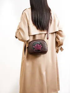 Detail of elegant lotus embroidery on vintage brown crossbody bag with gold hardware