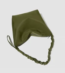 Detail view of olive green tote bag featuring ruched handle design and silver zipper closure