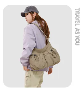 Détail du sac bandoulière en nylon kaki avec deux poches à cordon et texture froncée