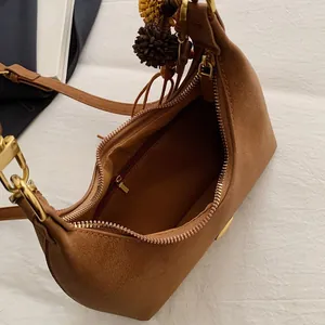 Brown suede underarm shoulder bag with top zipper and plush ball charm decoration