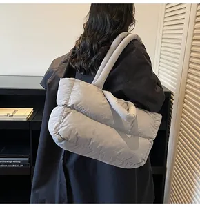Side view of puffy quilted tote bag in light grey being carried by a model