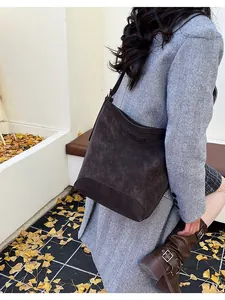 Brown suede bucket bag styled with a gray blazer and brown boots for a winter look