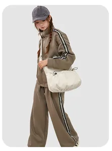 Détail d'un sac à bandoulière en nylon plissé blanc crème avec un jogging marron