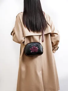 Detailed view of black Boston bag with purple lotus motif and gold zipper hardware