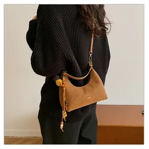 Detail of brown suede crescent bag with boho beads and colorful fringe tassel