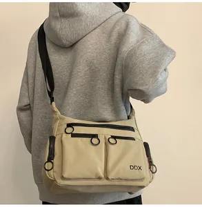 Detail view of khaki waterproof nylon crossbody bag with multiple zip pockets and wide strap