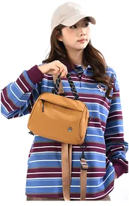 Detail of yellow nylon handbag featuring a woven handle and metallic M FASHION logo