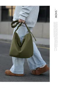 Detail showing the dark green tote bag with its signature pleated shoulder strap design