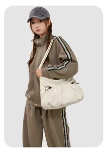 Détail d'un sac cabas en nylon crème avec cordons de serrage porté par un mannequin
