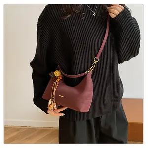 Close-up of wine red crescent bag with floral tassel detail and matte leather texture