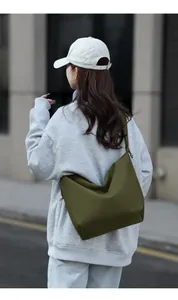 Rear view of an army green slouchy tote bag worn cross-body over a casual gray hoodie