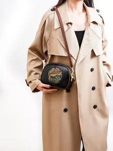 Detail of black Boston bag with colorful elephant relief and brown contrast shoulder strap