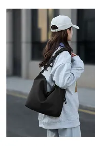 Detail of black tote bag featuring ruched ruffled strap and glossy nylon fabric texture