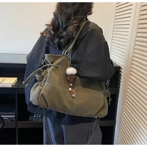 Detail of army green canvas tote bag with drawstring closure and plush pendant charm