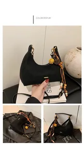 Detail of black crescent hobo bag featuring wood bead tassel and gold-tone hardware