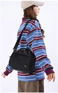 Close-up of black nylon shoulder bag featuring wide strap and circular metal logo detail