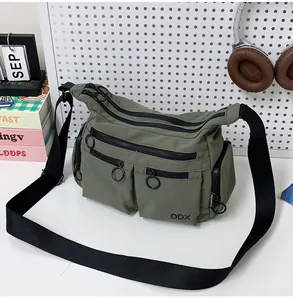Detail view of military green nylon crossbody bag with multi-pocket and ring zipper pulls