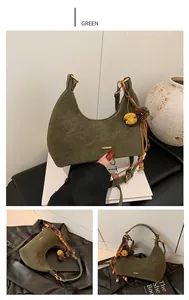 Detail view of green half-moon underarm bag featuring grain texture and fur pom-pom charm