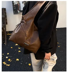 Detailed macro view of retro brown wax leather texture and metallic buckle on tote bag