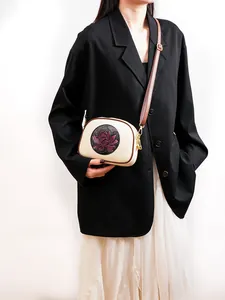 Detailed macro view of white leather Boston bag with vintage lotus emblem and gold hardware