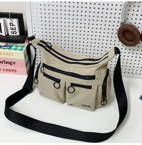Detail of beige nylon crossbody bag featuring multiple zipper pockets and DDX logo