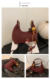 Detail of wine red crescent shoulder bag with floral bead charm and matte leather finish