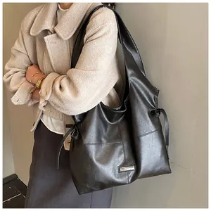 Detailed side view of large black leather tote bag with drawstring and silver logo plate