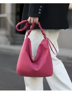 Detailed view of magenta hobo bag featuring a unique pleated shoulder strap design