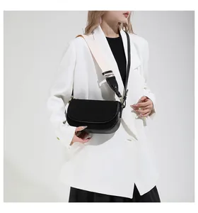 Detail of black saddle bag featuring gold metal buckle and dual strap options