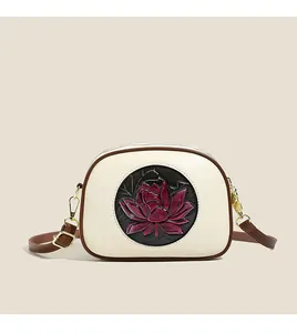 Detail of Boston bag featuring embossed red lotus on a circular black leather patch