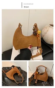 Detail of brown suede crescent bag featuring wooden beads, woven tassels, and pom-poms