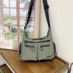 Green nylon crossbody bag with multi-zipper pockets and black adjustable strap for commuting