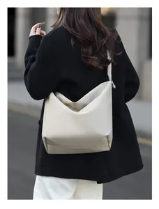 Rear view of cream crossbody bucket bag with minimalist wide strap on model