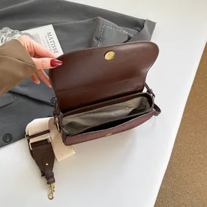 Minimalist brown crossbody bag with interior pockets and adjustable woven strap