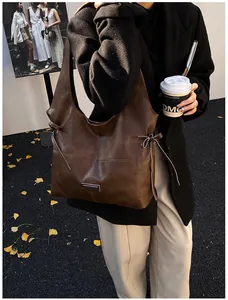 Detail view of large brown vintage tote bag with side bow and metallic logo plate