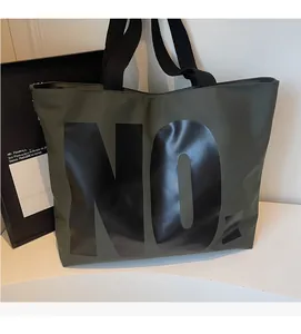 Detail of olive green canvas tote bag with bold NO. lettering and durable web handles