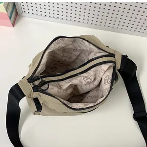 Spacious interior of beige nylon crossbody bag with branded lining and dual zippers