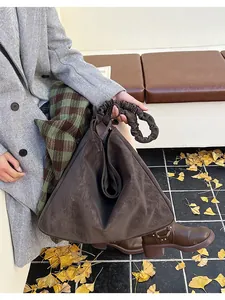 Detail of a large dark brown suede tote bag with pleated cloud handle and origami design
