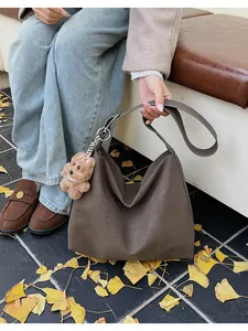 Detail of dark brown leather tote with silver rings and cute plush bear accessory