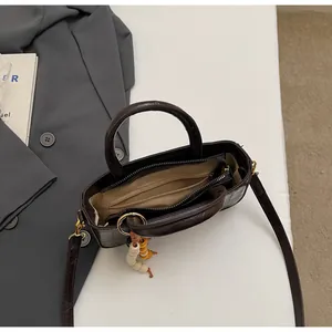 Bolso cubo marrón oscuro efecto cocodrilo con asas y borla decorativa de cuentas