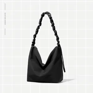 Minimalist black tote bag with adjustable pleated shoulder strap and matte nylon finish