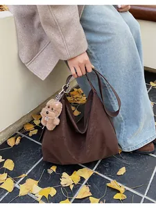 Detail of dark brown faux leather tote with plush bear charm in an autumn setting
