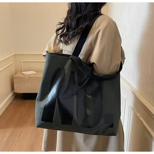 Large dark green canvas tote bag with black NU. logo shown on model for size and style