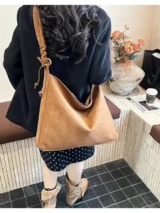 Brown faux suede tote bag featuring unique knot strap detail and a slouchy hobo design