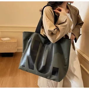 Close-up of military green canvas tote bag with bold NO. letter print and black strap