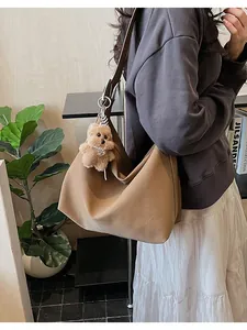 Close-up of brown PU leather hobo bag with a cute plush teddy bear charm accessory