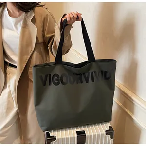 Close-up of olive green canvas tote bag with black VigourVivid print on luggage