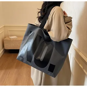 Detail of grey canvas tote bag with black NO print and wide shoulder strap on model