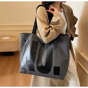 Detail of dark grey tote bag with bold NO. lettering and wide black shoulder strap